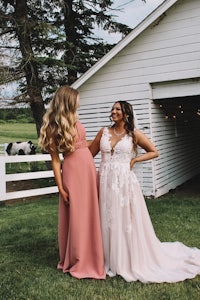 two bridesmaids standing in front of a barn