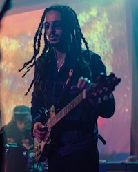 a man with dreadlocks playing a guitar on stage