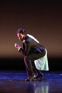 a dancer crouching on stage in a tuxedo