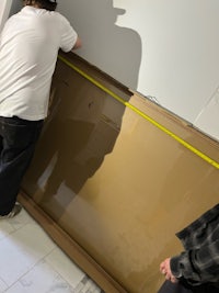 two men working on a wall in a bathroom
