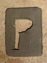 the letter p is cut out of a piece of wood