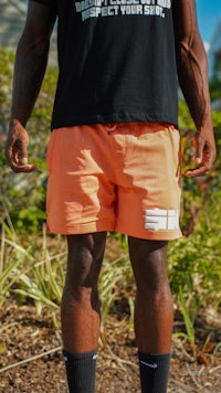 a man wearing orange shorts and a black t - shirt