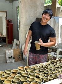 a man smiling in front of a table full of cups
