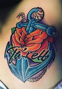 a tattoo with an anchor and rose on the chest