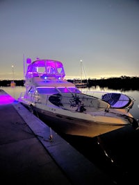 a boat docked at night with purple lights on it