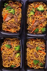 asian beef noodles in plastic containers with broccoli and carrots