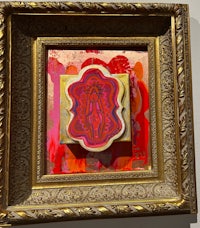 a gold framed painting with a red and pink design