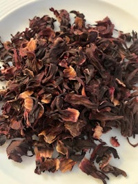 a pile of dried hibiscus flowers on a white plate