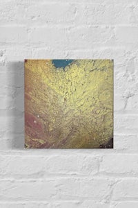 a canvas print of a yellow and gold painting on a brick wall