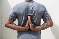 a man in a gray shirt with tattoos on his back
