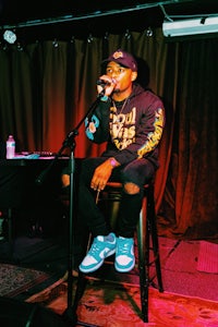 a man sitting on a stool in front of a microphone