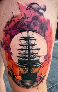 a tattoo of a sailboat on a man's thigh