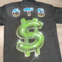 a black shirt with a green dollar sign on it