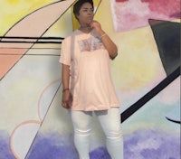 a woman wearing a pink t - shirt and white pants