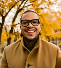 a man wearing glasses and a coat in a park