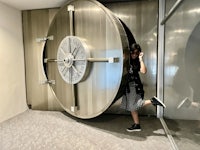 a woman standing in front of a large bank vault