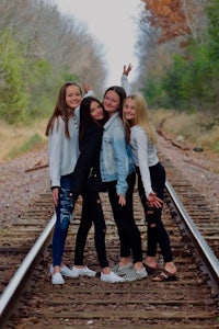a group of girls posing for a photo on a train track