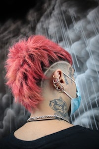 a man with a red mohawk and tattoos in front of a cloud