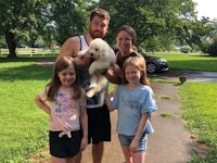 a family poses with a white dog on a sidewalk