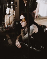 a man with tattoos sitting on a drum set