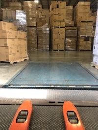 two orange pallet jacks in a warehouse