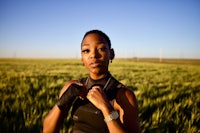a black woman standing in a field with a boxing glove