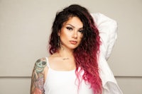 a woman with pink hair and tattoos posing for a photo