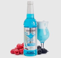 a bottle of blue gin with berries and a glass next to it