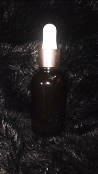 a black bottle with a white lid sitting on a furry surface
