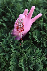 a pink hand holding a red necklace