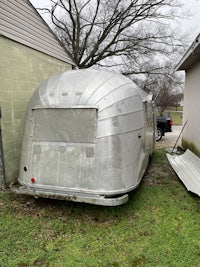 a silver airstream trailer parked in a grassy area