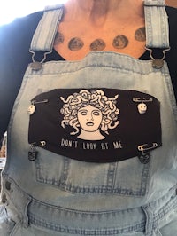a woman wearing overalls with a tattoo saying don't look at me