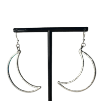 a pair of silver crescent earrings on a black stand