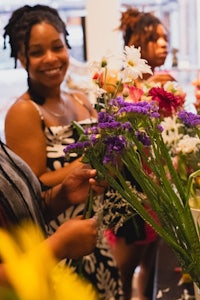 a group of women are arranging flowers at a table