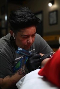 a tattoo artist is getting a tattoo on a man's arm