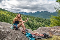 a woman sitting on top of a rock taking a selfie