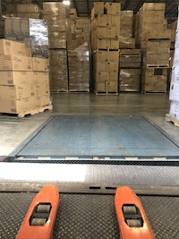 two orange forklifts moving boxes in a warehouse