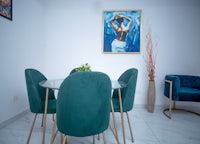 a dining room with green chairs and a painting on the wall