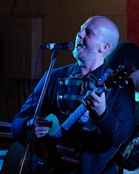a bald man singing into a microphone