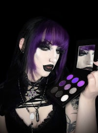a woman holding a purple eyeshadow palette