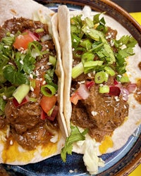 two tacos with meat and vegetables on a plate