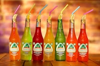 five bottles of juice with straws sitting on a wooden table