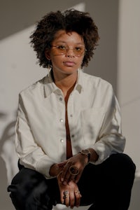 a woman in a white shirt and black pants sitting on a chair