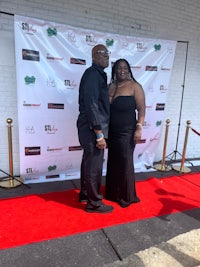 a man and woman standing on a red carpet