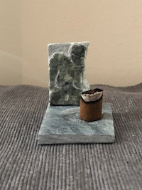 a small incense holder with a piece of stone on it