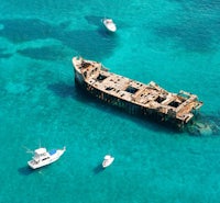 a boat is in the water next to a wrecked ship