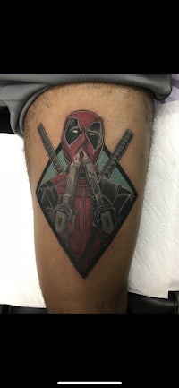 a deadpool tattoo on a man's thigh