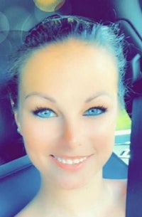 a woman with blue eyes smiling in a car