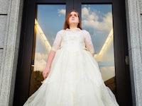 a young woman in a wedding dress standing in front of a building