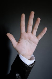 a person's hand is raised in front of a dark background